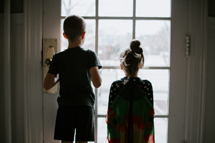 Siblings look out the window together.