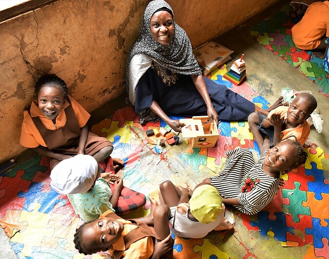Children sit in a circle learning with an adult.