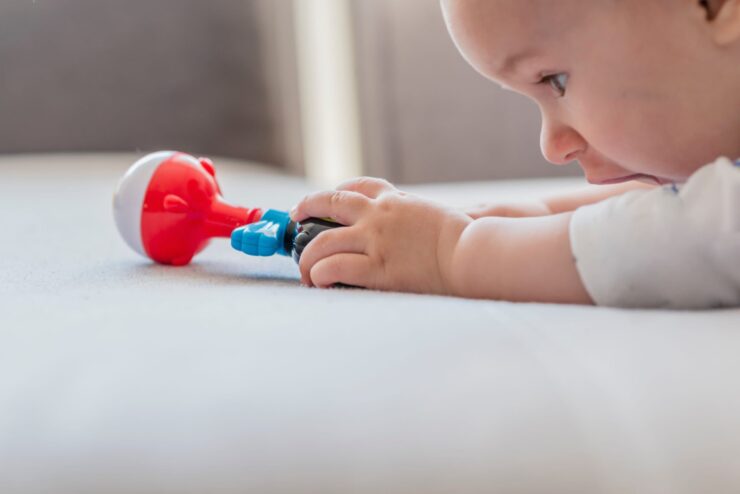 An infant reaches out for a toy.
