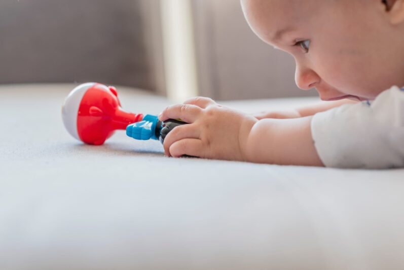 An infant reaches out for a toy.
