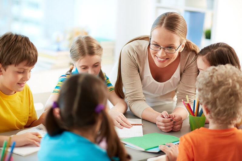 A teacher talks to students at a table.