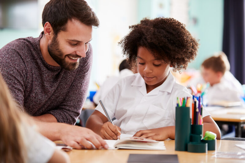 A teacher helps a child learn in the classroom.