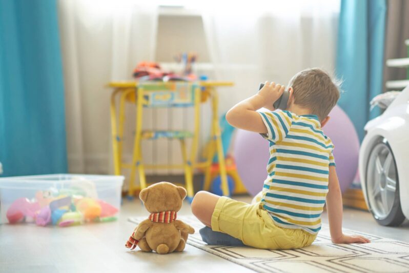 A young boy intently listens to a speaker held to his ear.