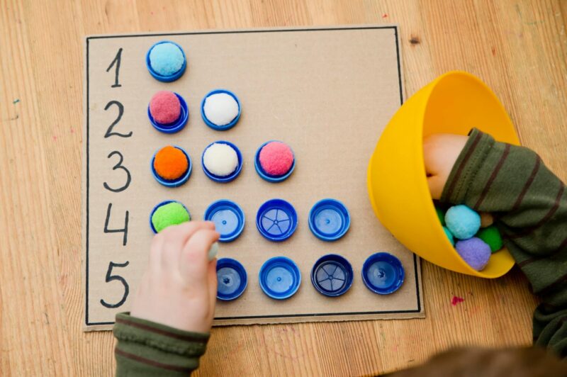 A child counts out small pom-poms.