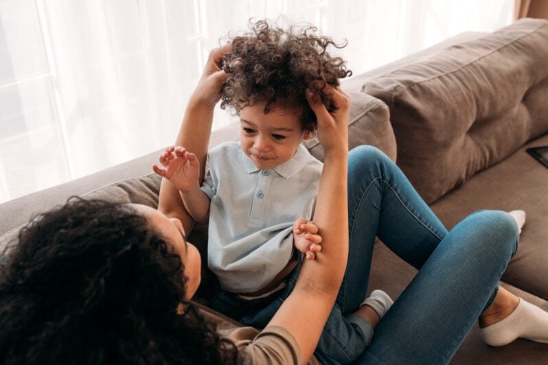 A happy toddler interacts with their parent.