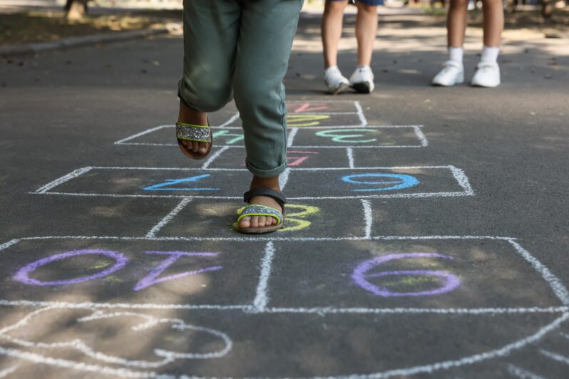 Children play hopscotch in the street.