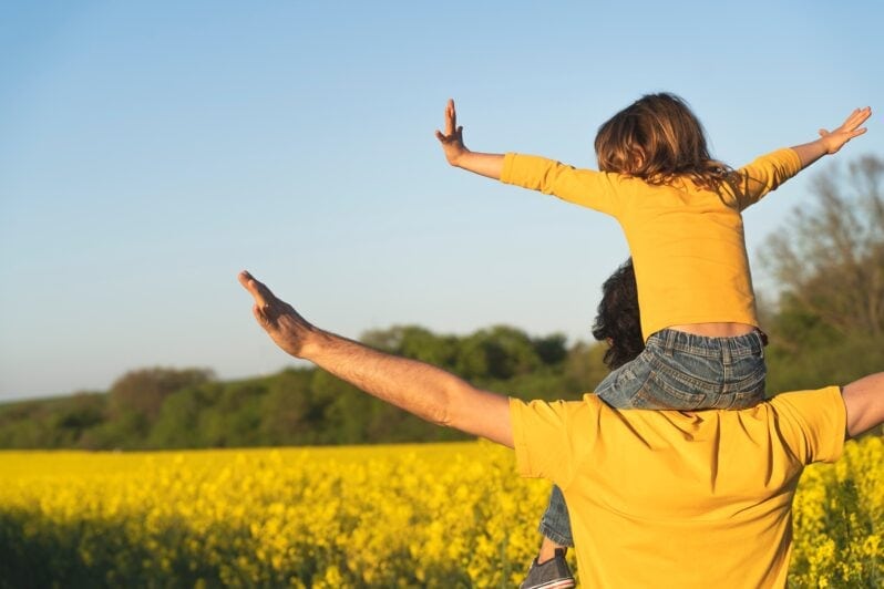 A child sits on their father's shoulders.