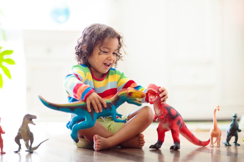 A child plays with toy dinosaurs.