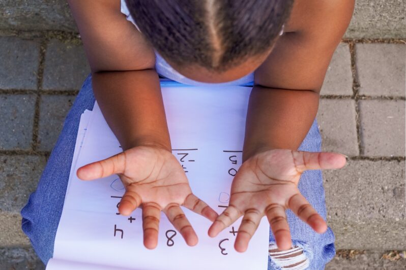 A child counts with her fingers.