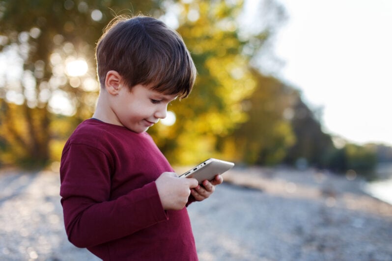 A child plays on a tablet outside.