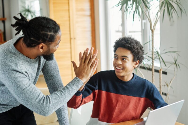 An adult gives a learner a high five.