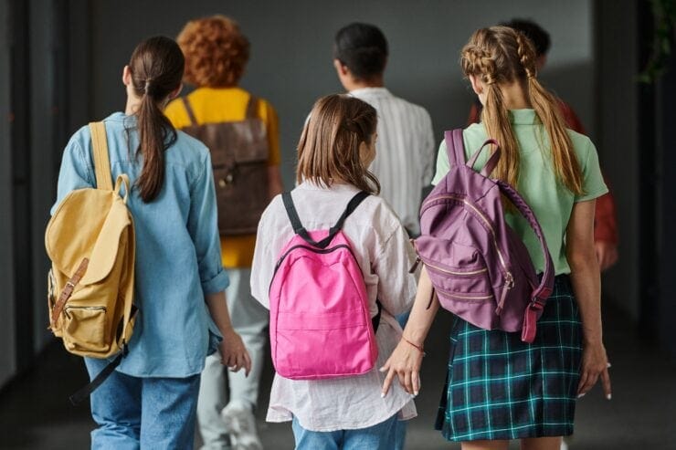 Teenagers walk along a school corridor.