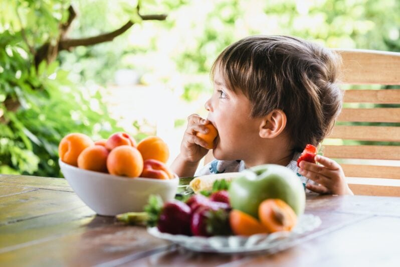 A child eats fruit from a bowl.