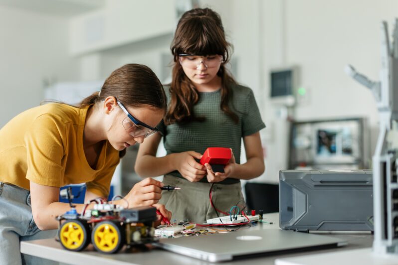 Two students build a robotic car.