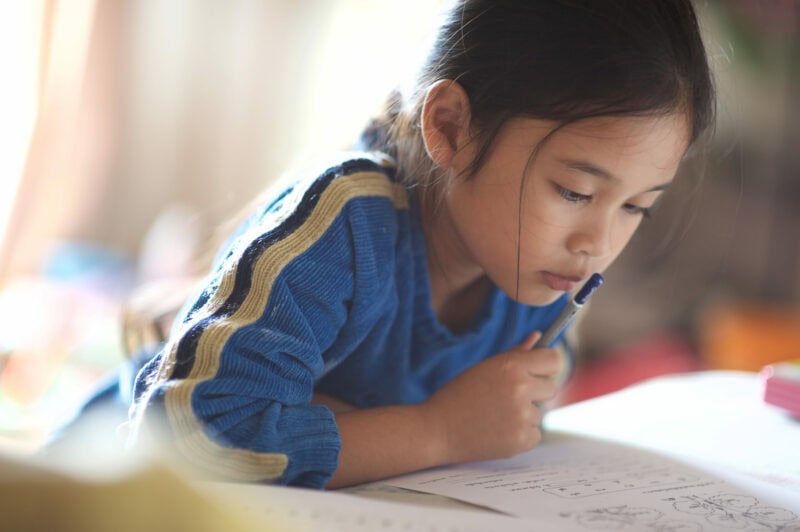 A young girl thinks while working on her homework.