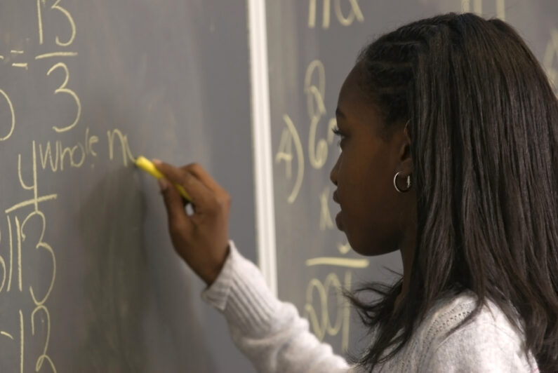 A student writes on a chalkboard.