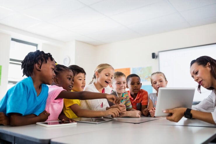 An educator teaches a group of students with a tablet.