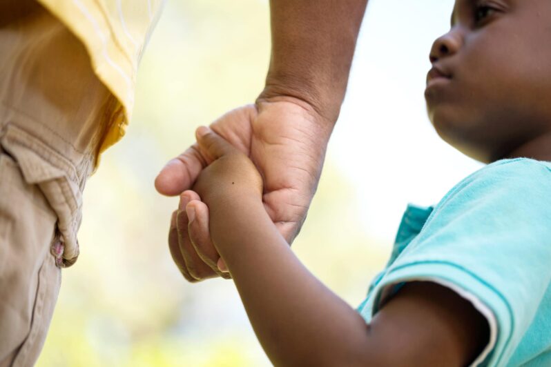 A caregiver holds a child's hand.